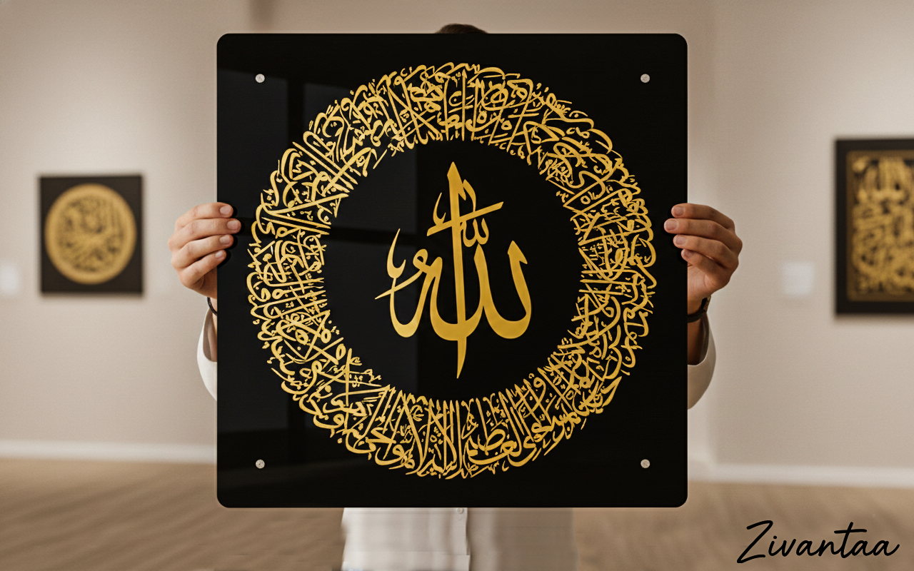 Person holding a black board with gold Arabic calligraphy in a room with other decorative items.
