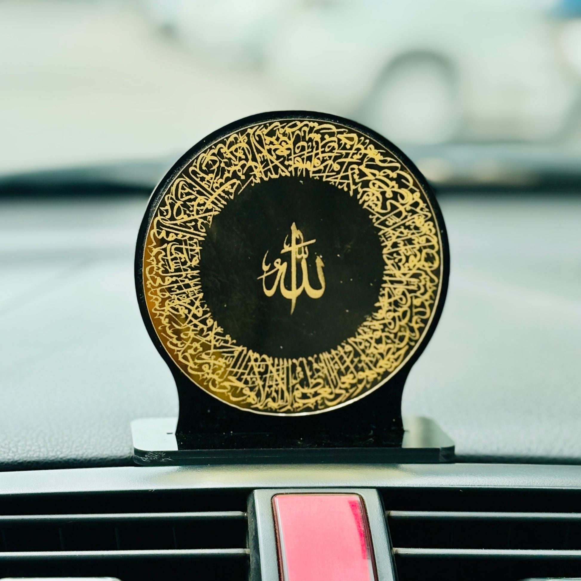 Decorative item with gold calligraphy on a car dashboard