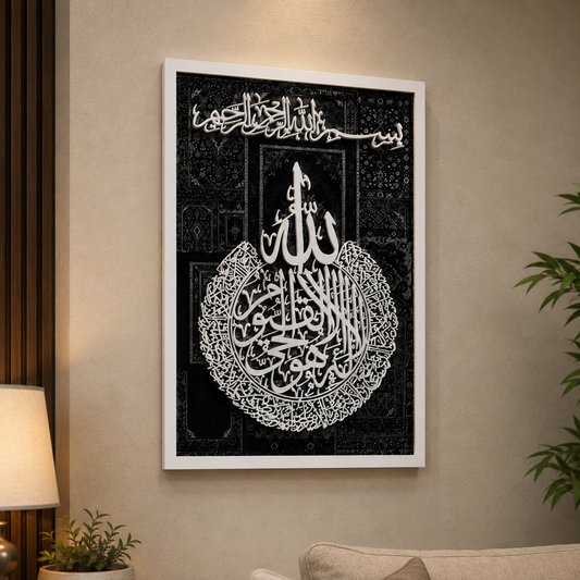 A framed black and white Islamic wall art print featuring Arabic calligraphy, displayed on a beige wall in a modern living room setting.