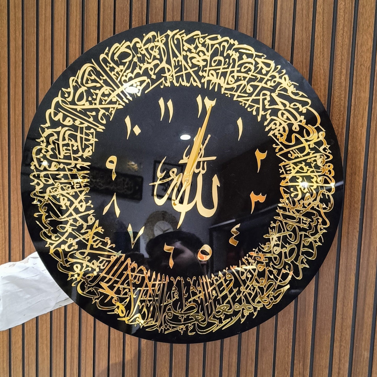 Decorative wall clock with Arabic calligraphy on a wooden panel background