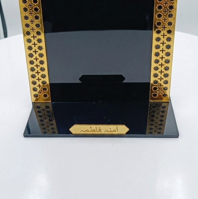 Decorative black and gold frame with intricate patterns on a white surface