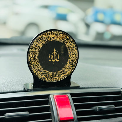 Decorative car dashboard accessory with gold patterns and 'Allah' symbol on a black background.