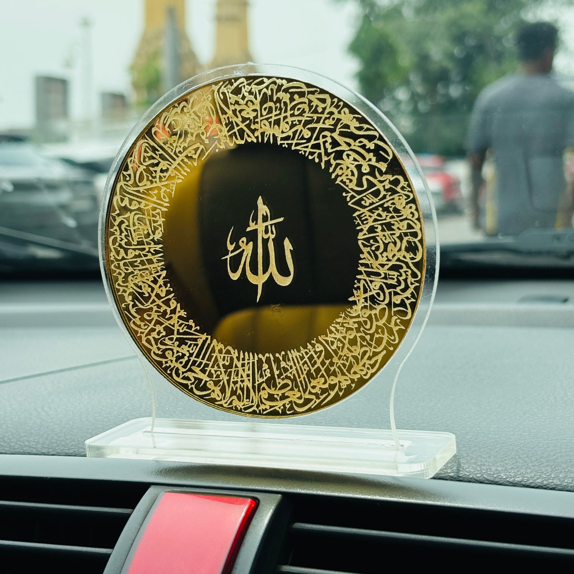 Decorative plate with gold calligraphy on a car dashboard