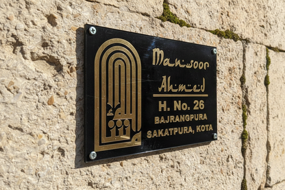 Black and gold nameplate on a stone wall