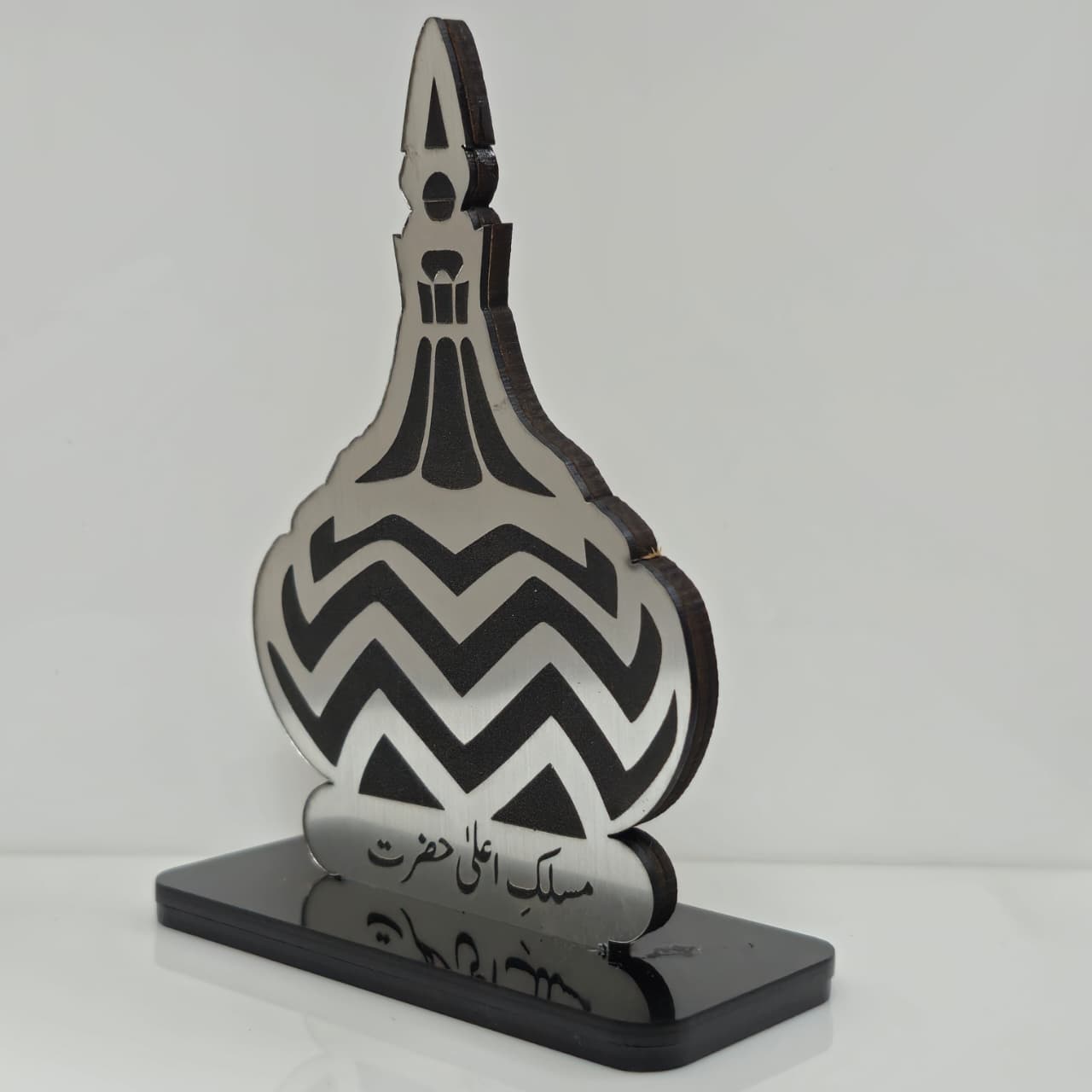 Decorative bottle-shaped object with black and white pattern on a gray background
