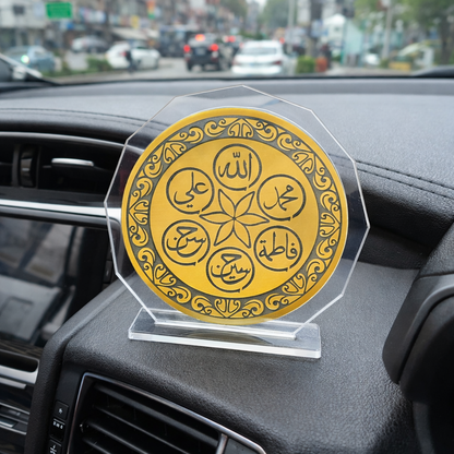 Decorative gold coin with Arabic text on a clear stand inside a car.