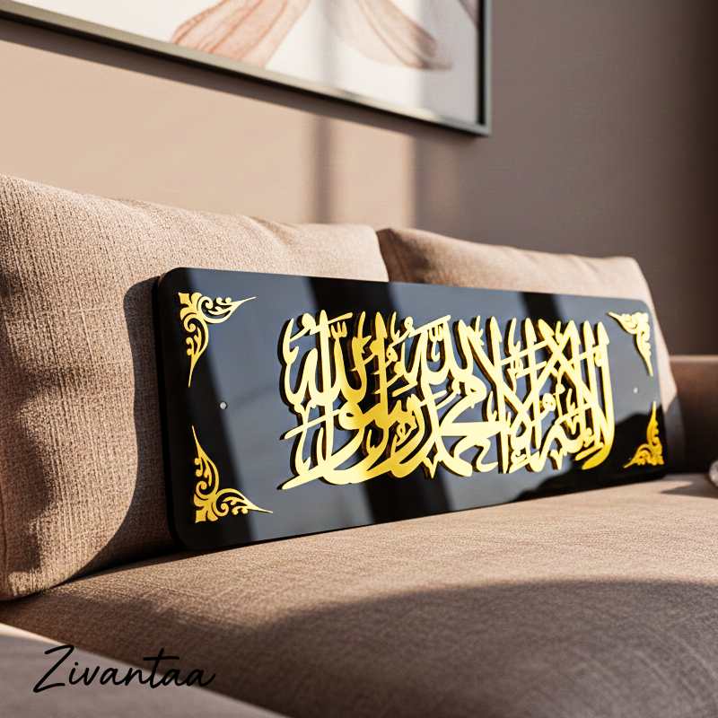 Decorative wall art with gold Arabic calligraphy on a black background, placed on a brown sofa.