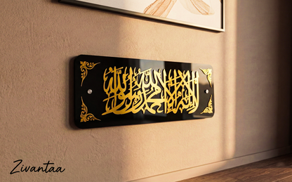 Decorative wall plaque with gold Arabic calligraphy on a black background, mounted on a beige wall.