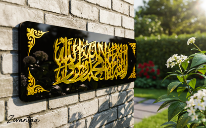Decorative wall art with gold calligraphy on a black background mounted on a brick wall.