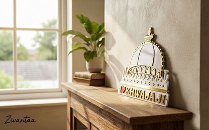 Decorative crown mirror with 'KHWAJA' text on a wooden surface near a window.