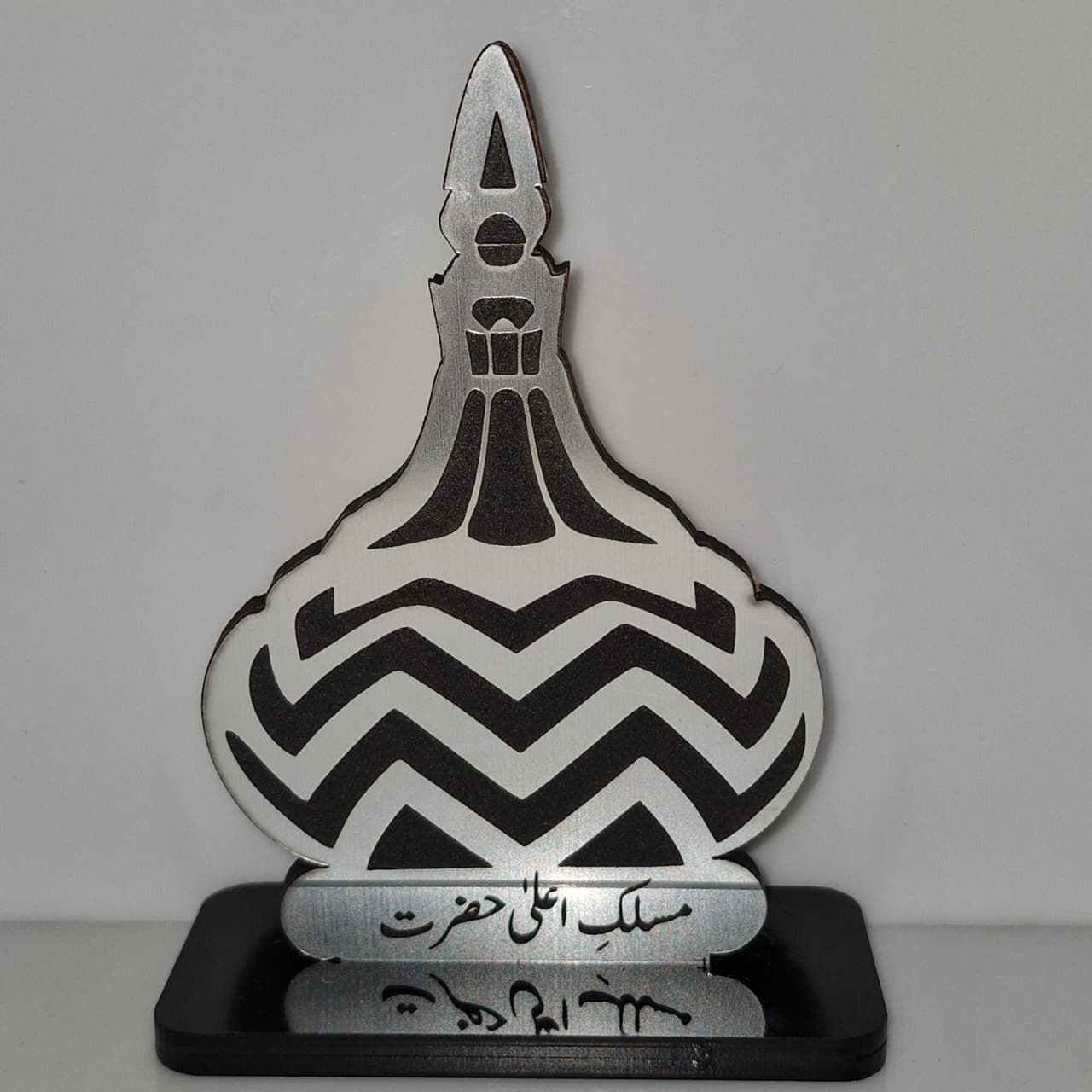 Decorative item with chevron pattern and Arabic text on a gray background