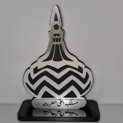 Decorative item with chevron pattern and Arabic text on a gray background