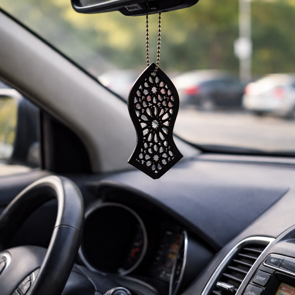 Decorative car hanging on a car's rearview mirror with a blurred road and cars in the background