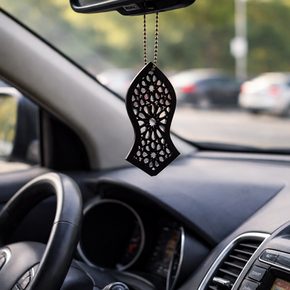 Decorative car hanging on a car's rearview mirror with a blurred road and cars in the background