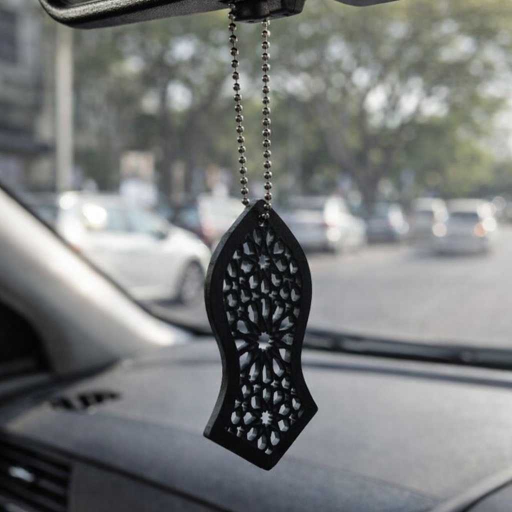 Car hanging ornament on a car's rearview mirror with a blurred street view in the background