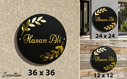 Round black sign with gold text and leaf designs, displayed on a wall and wooden surface.
